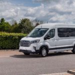 A school minibus parked on a leafy street.