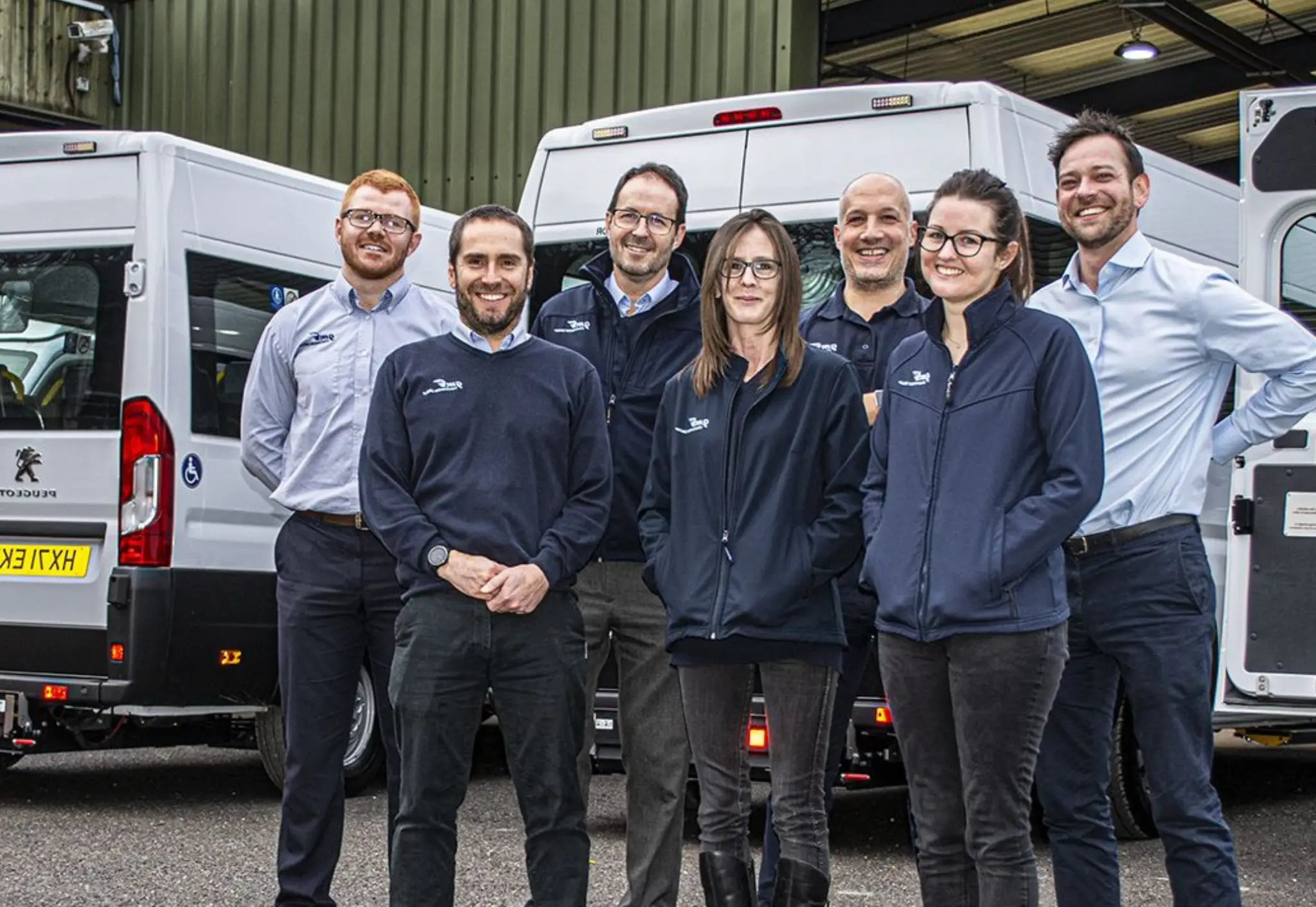 A team photo of GM Schol Minibuses outside the Devon warehouse.
